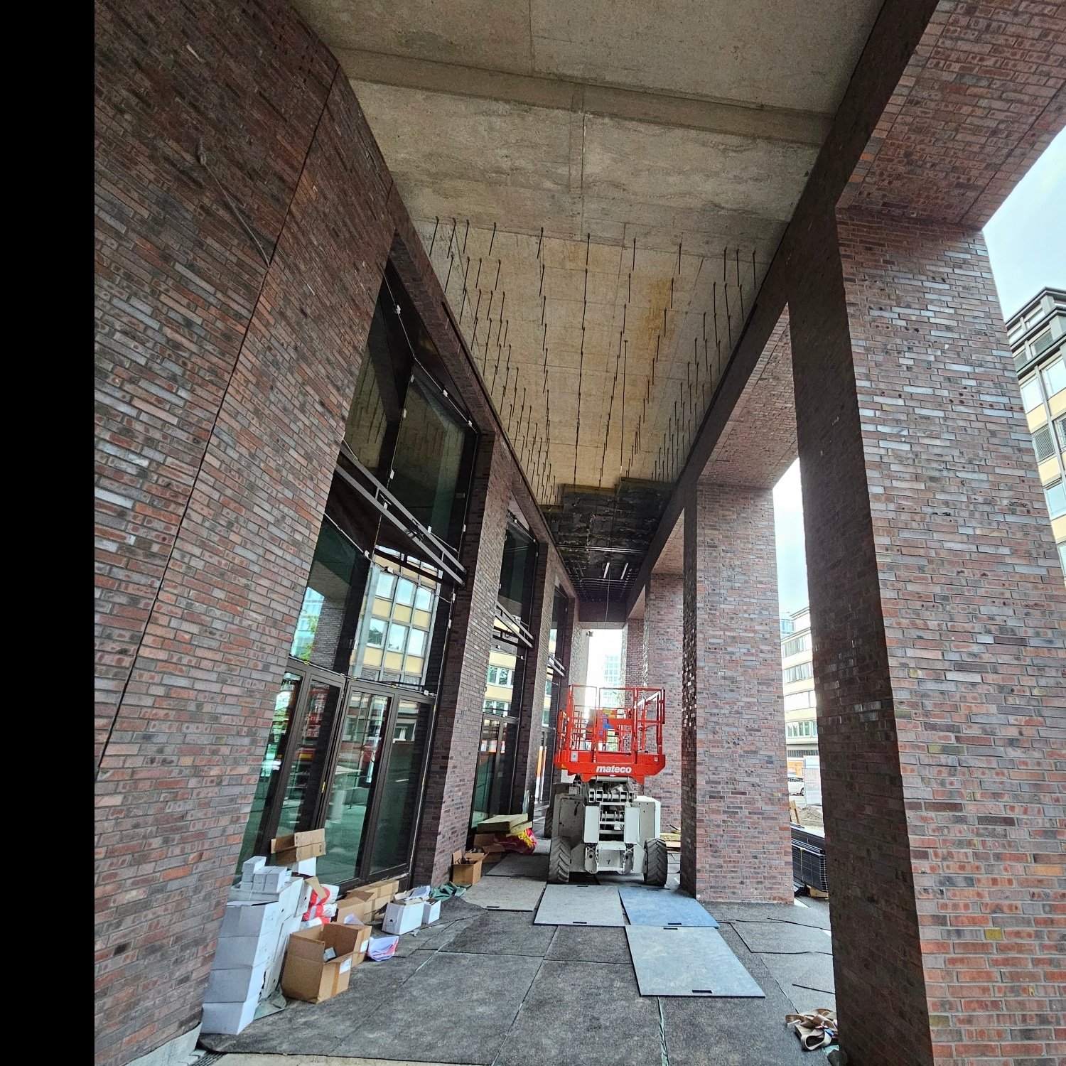Eingangsfoyer mit Backstein und sichtbarer Betondecke